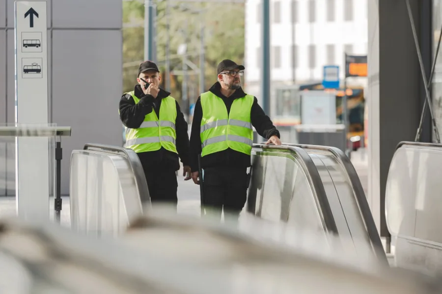 Deux agents en gilet de haute visibilité près d’un portique de contrôle