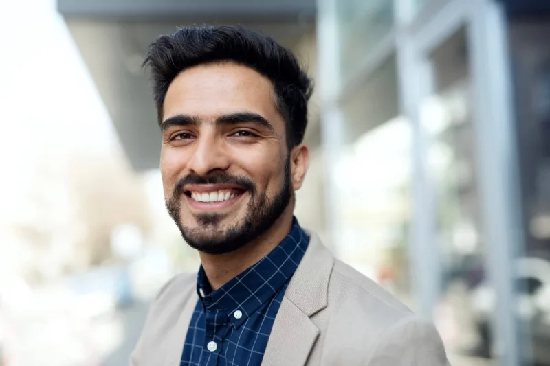 Homme souriant en veste claire, photographié en extérieur